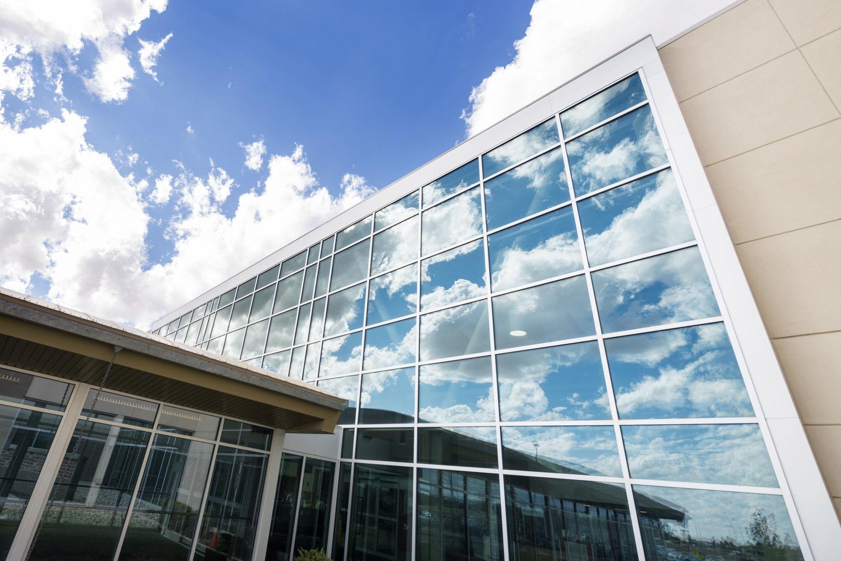 Low angle view of modern hospital building with reflection of clouds on glass windows